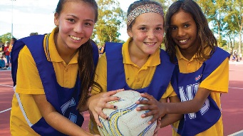 Three junior netballers holding a netbal