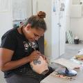 Revealed 2017 Professional Development - Ceramics. Photo by Jessica Wyld. Aboriginal girl painting a ceramic vase.