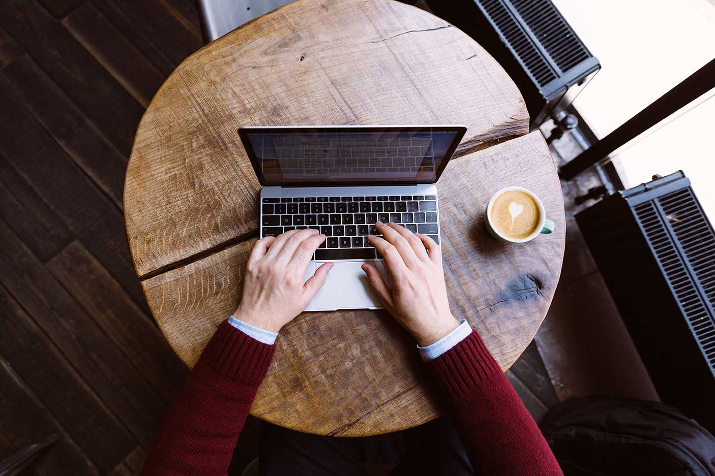 Directly above view of a man working on laptop in coffee shop, personal perspective view - stock photo