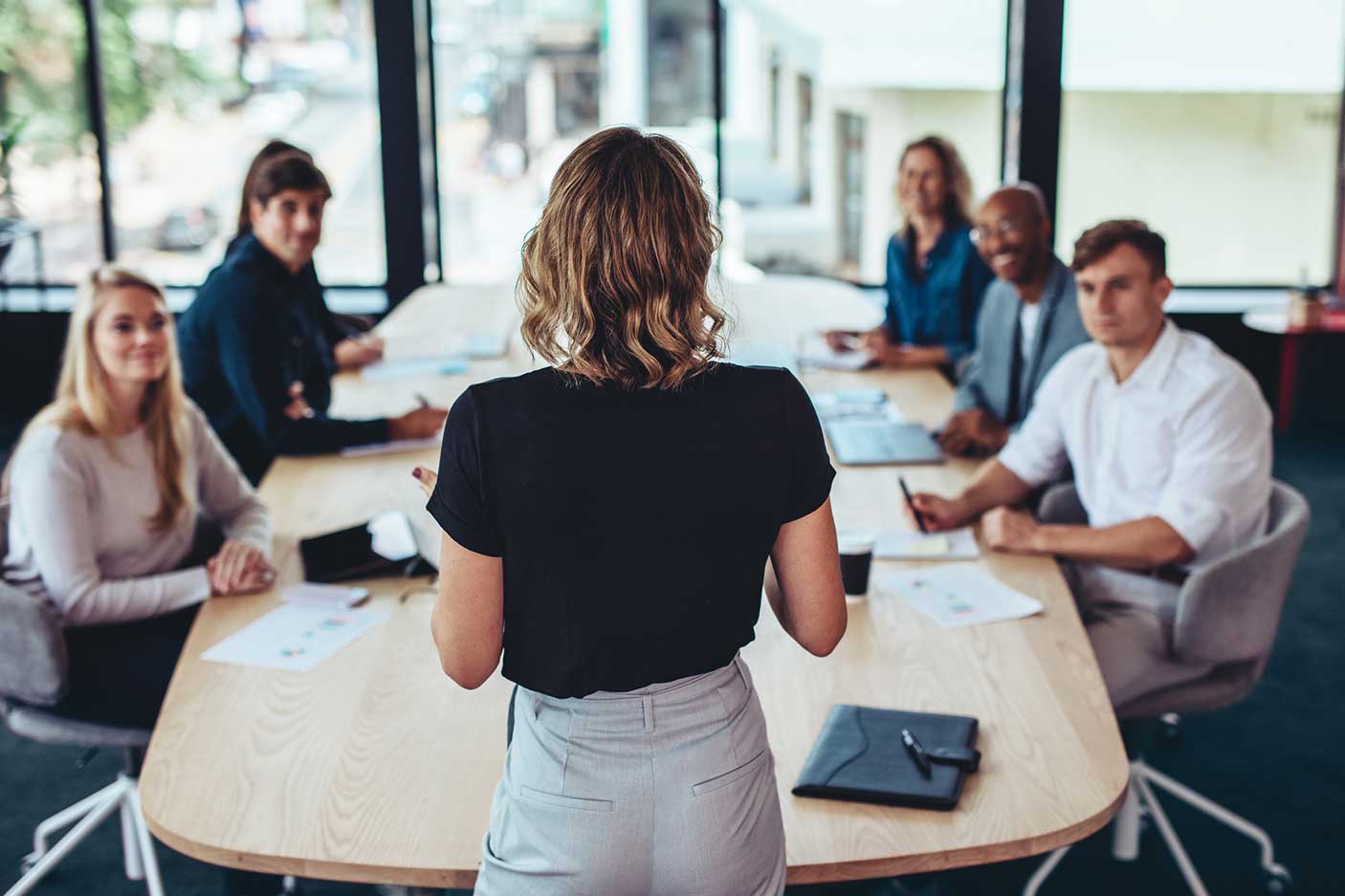 Rear view of a businesswoman addressing a meeting in office. Female manager having a meeting with her team in office boardroom.