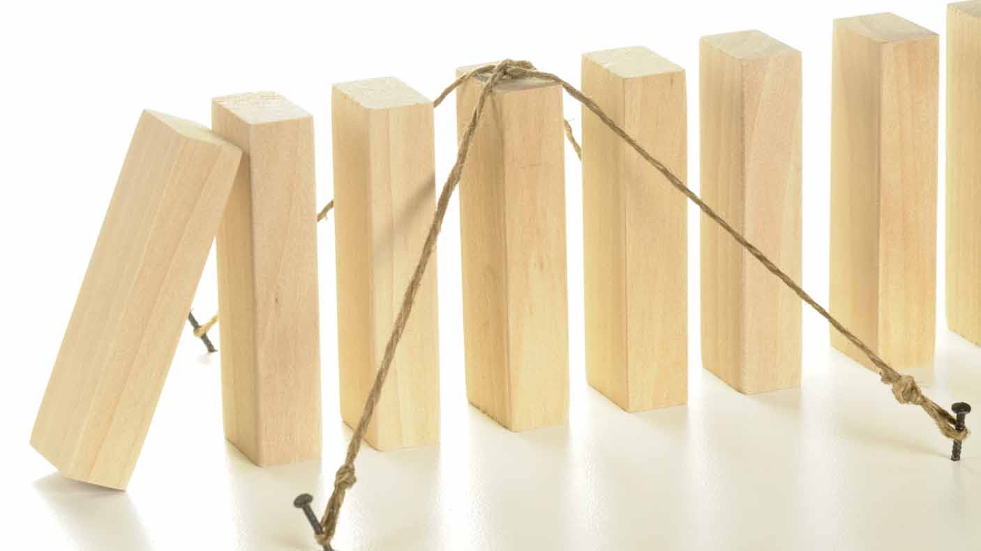 Insurance, business concept showing wooden blocks standing up in a row with string holding down one block.