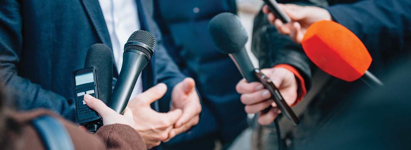 A media conference showing microphones pointing to a speaker