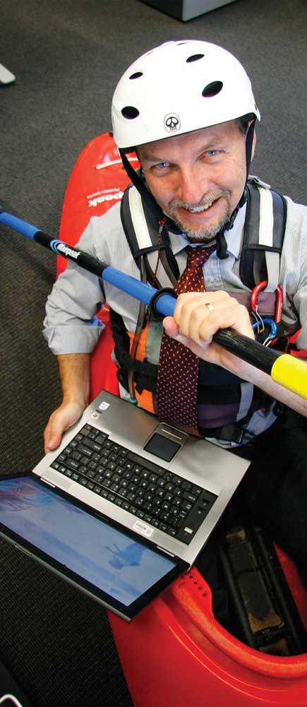 Steve Bennett holding a laptop in a kayak