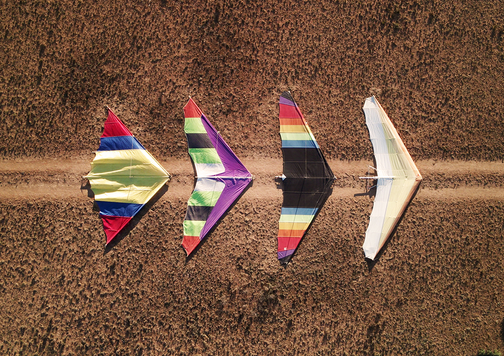 Four hang gliders on a sandy road