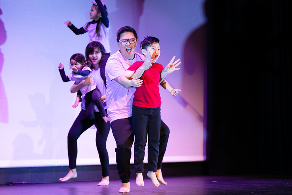 Two adults and three children performing on stage.