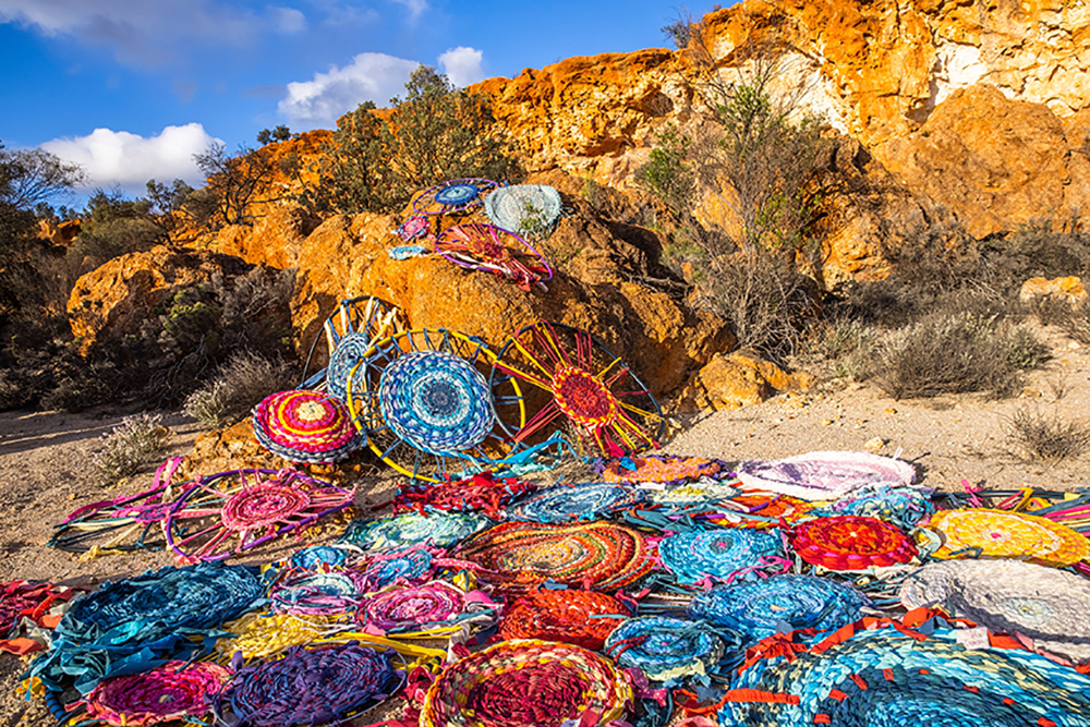 Woven rugs placed on rocks and ground.