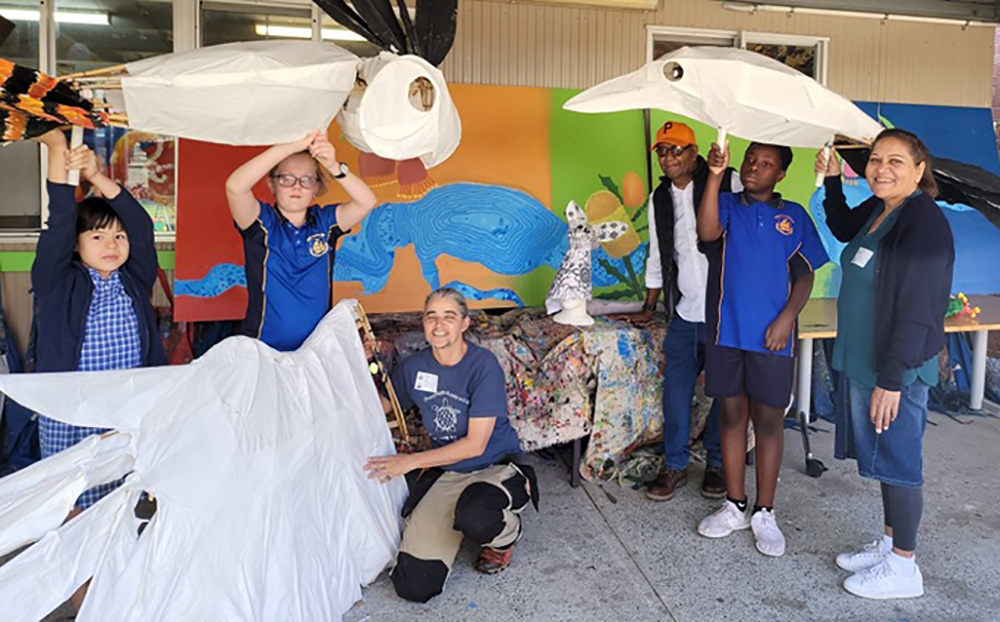 A group of students and teachers holding some large sized puppets.