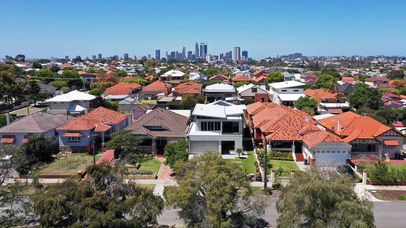 A suburban street with houses and in the background is the Perth CBD skyline.
