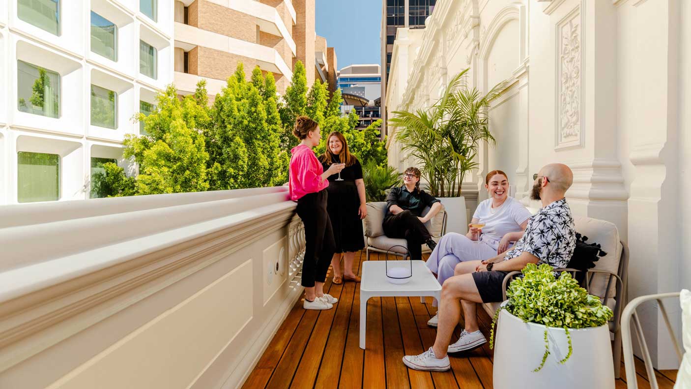 A group of people socialising on the balcony at His Majesty's Theatre.