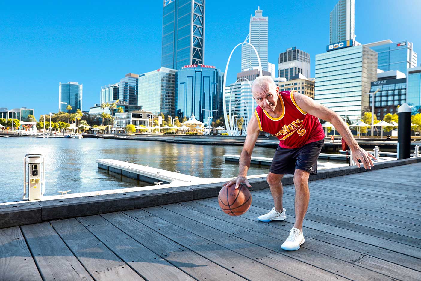 A man dribbling a basketball on a boardwalk in Perth