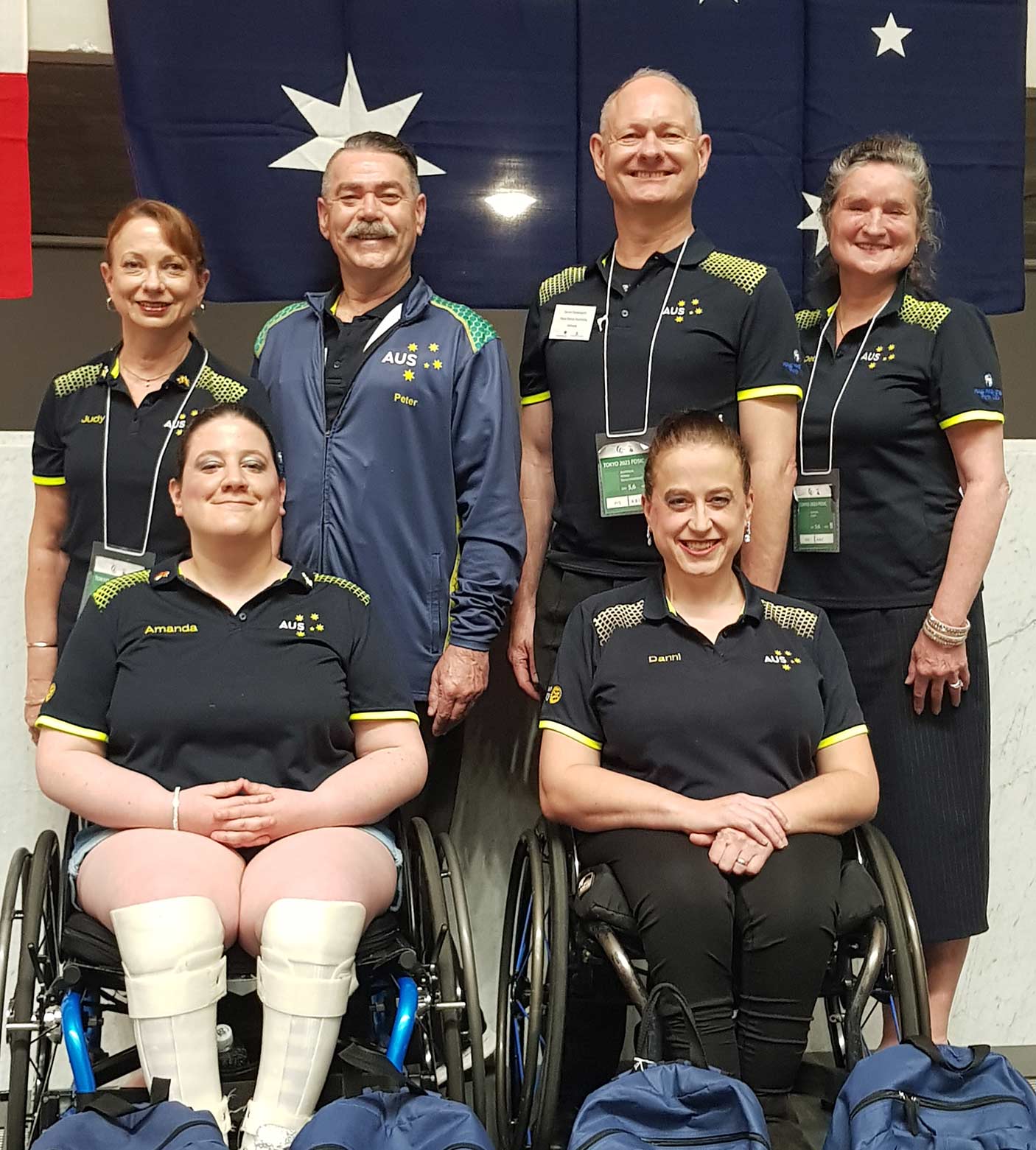 A group of Para-athletes in uniform with an Australian flag behind them