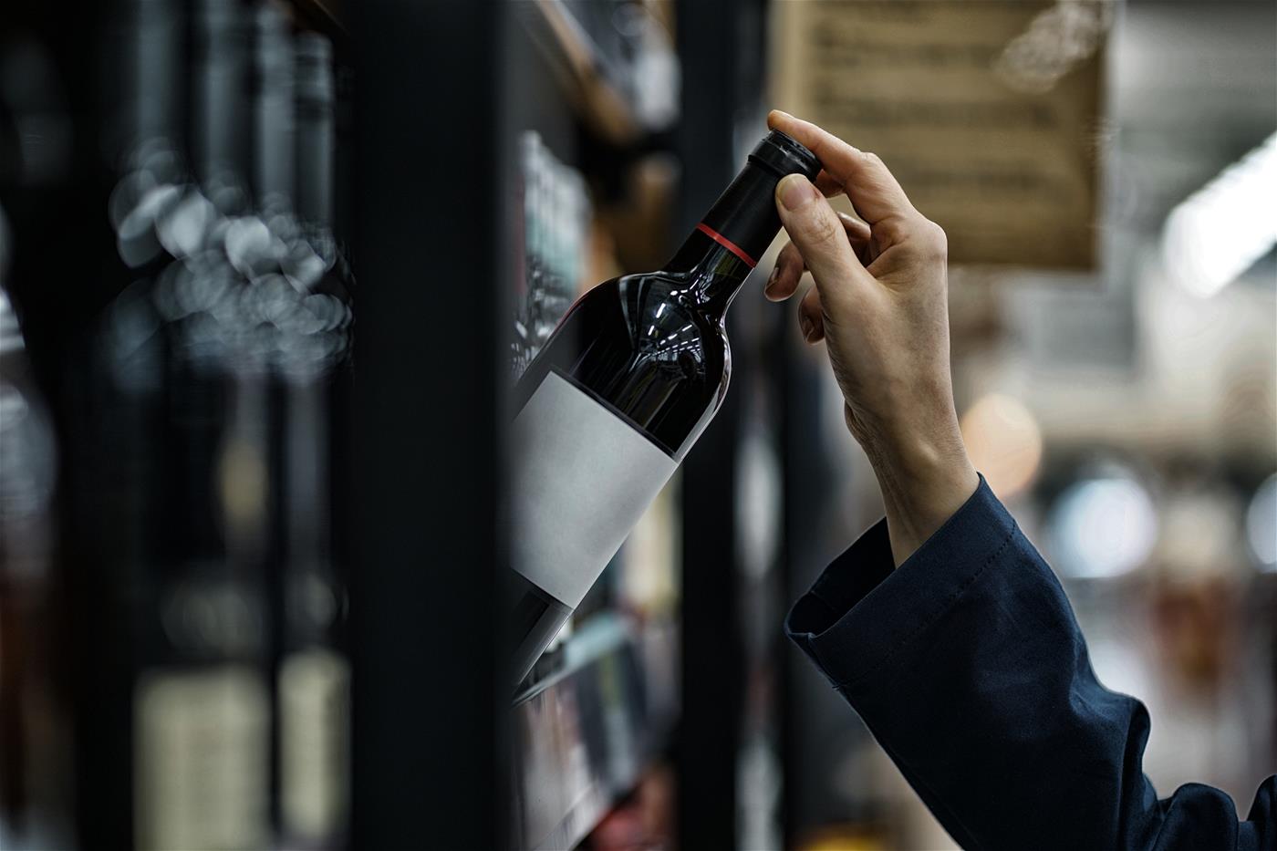 Hand picking a bottle of wine up from shelf