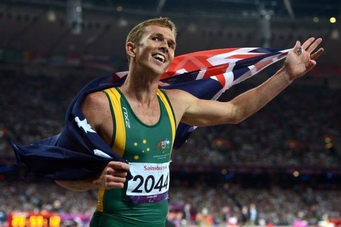 Brad Scott at the Paralympic Games holding an Australian flag