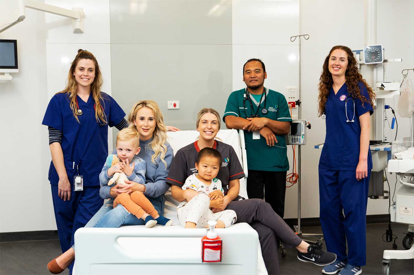 Nurses and patients sitting on a hospital bed and standing next to it