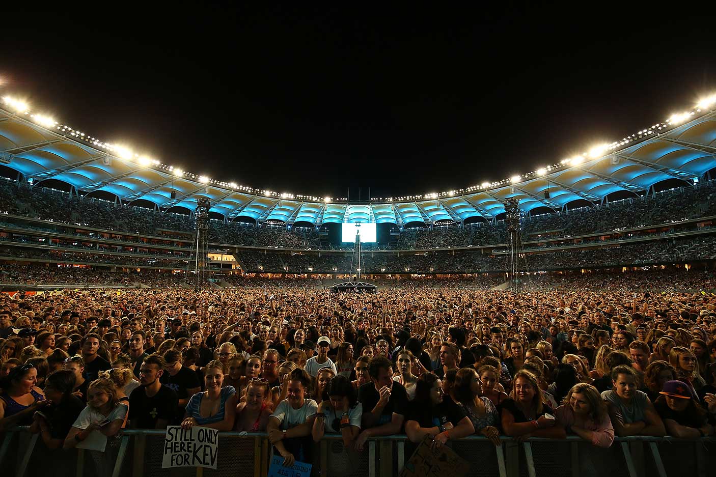 A crowd of concert-goers waiting for Ed Sheeran to perform at Optus Stadium in the evening.