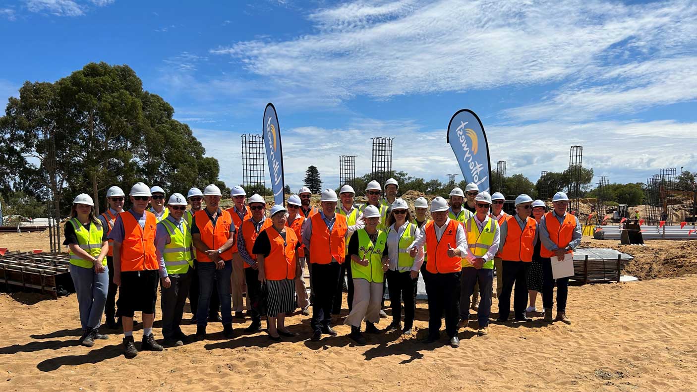 A group of people wearing high vis and hard hats standing on a cleared site