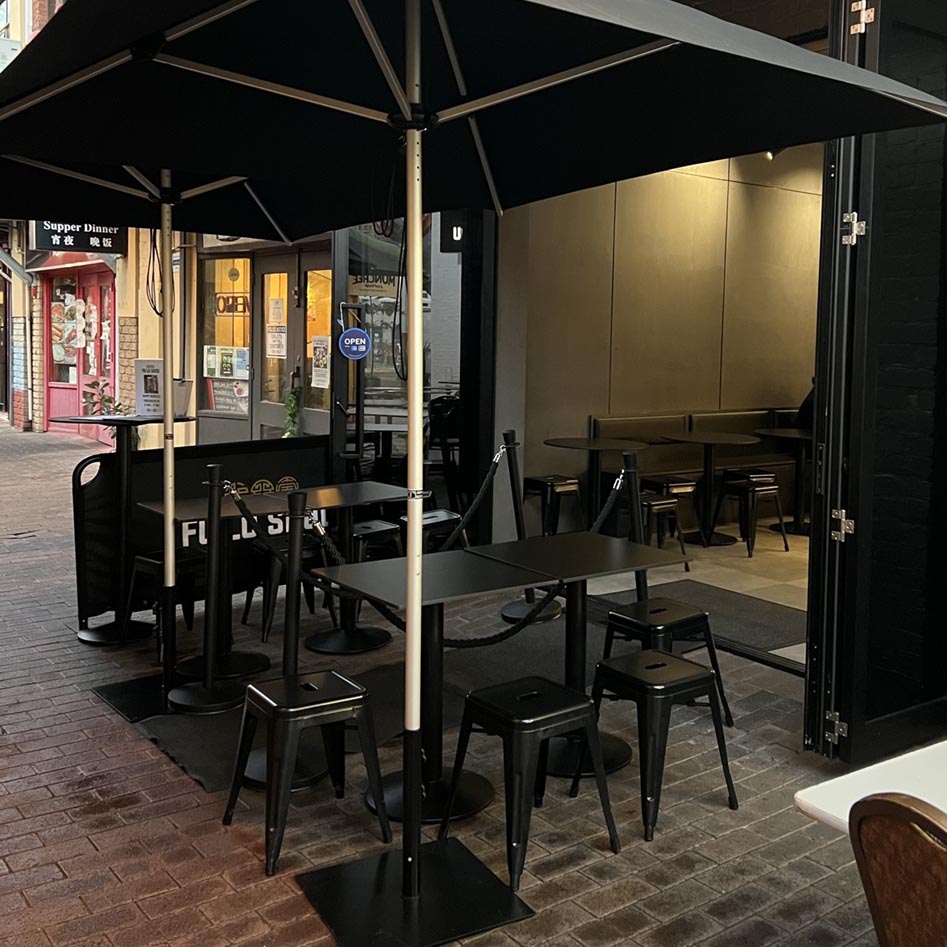 An alfresco area outside a hospitality venue with tables, chairs and umbrellas