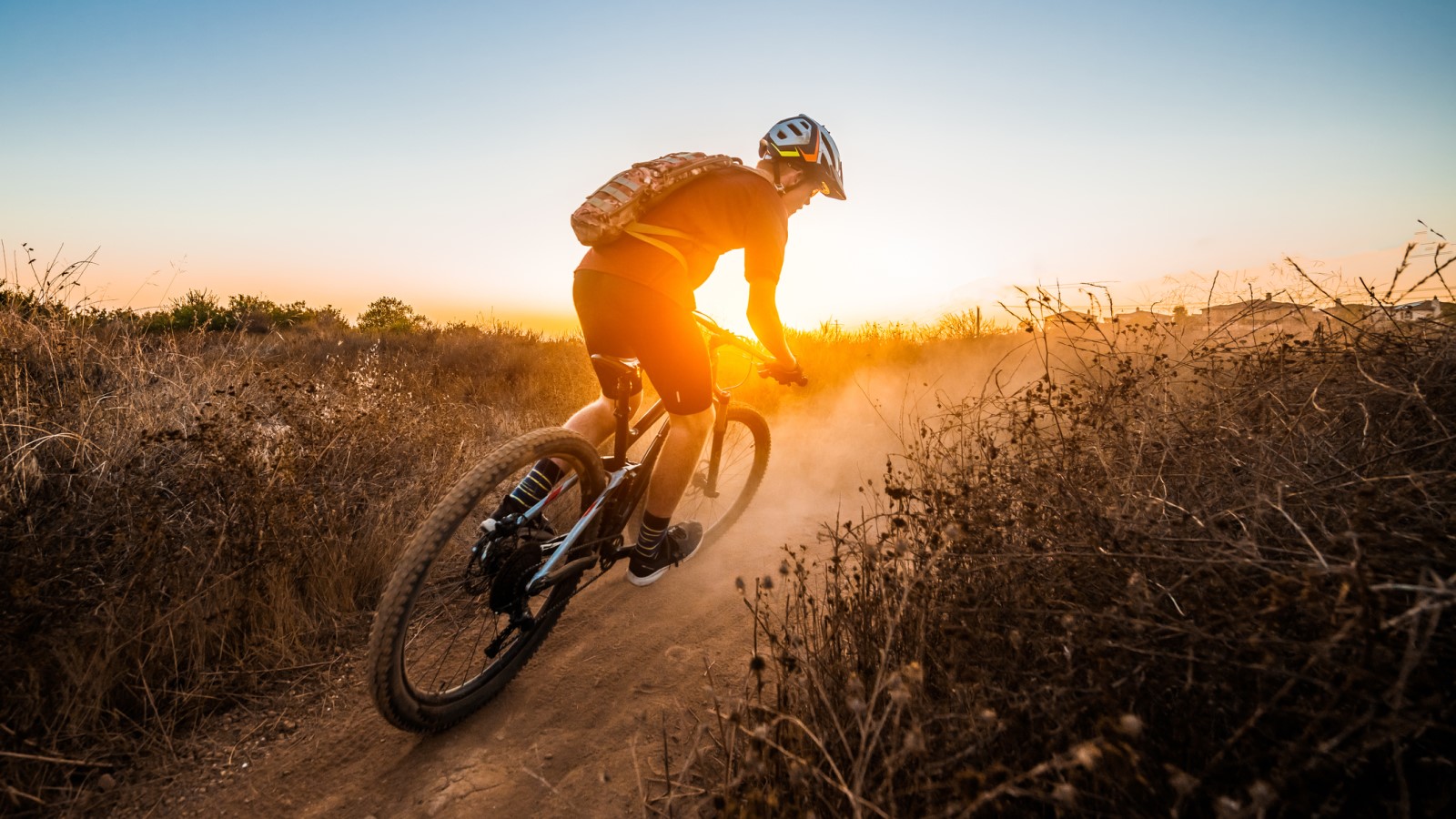 Mountain bike rider on coastal sand dunes at sunset.