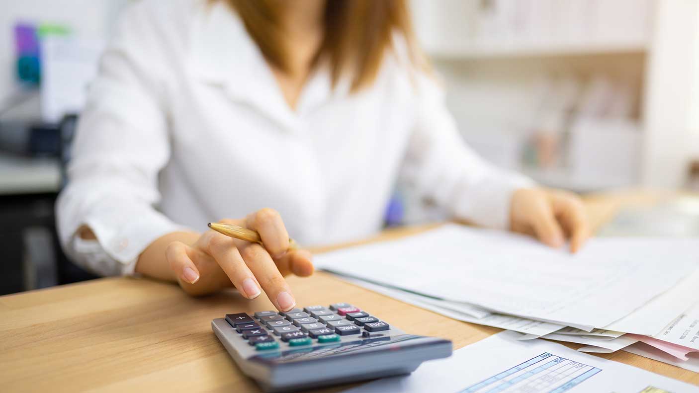 A woman sitting at a desk using a calculator