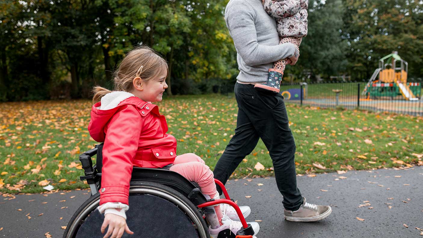 A low-angle side view of a father and his young daughters enjoying a lovely autumn day out in a public park.