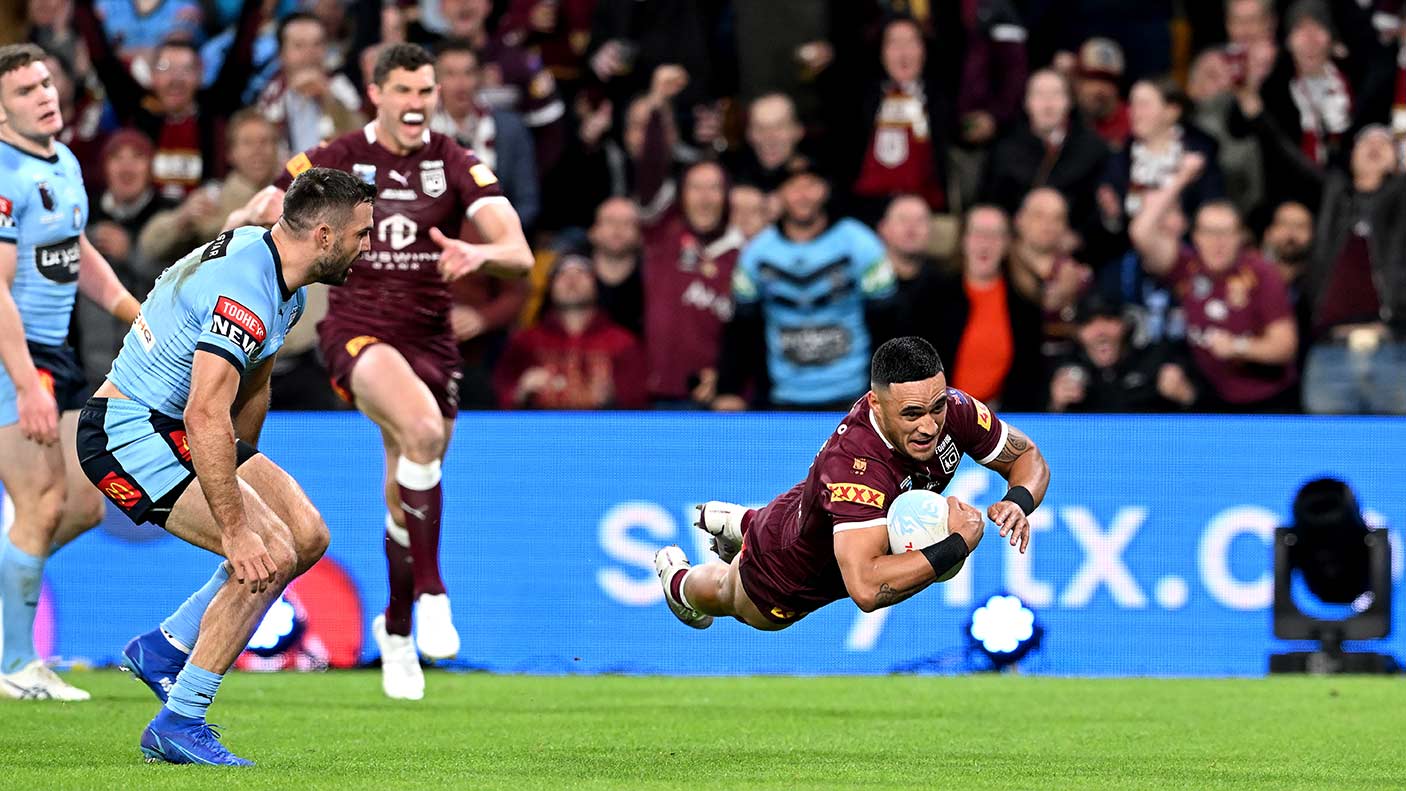 A rugby league player jumping to score a try