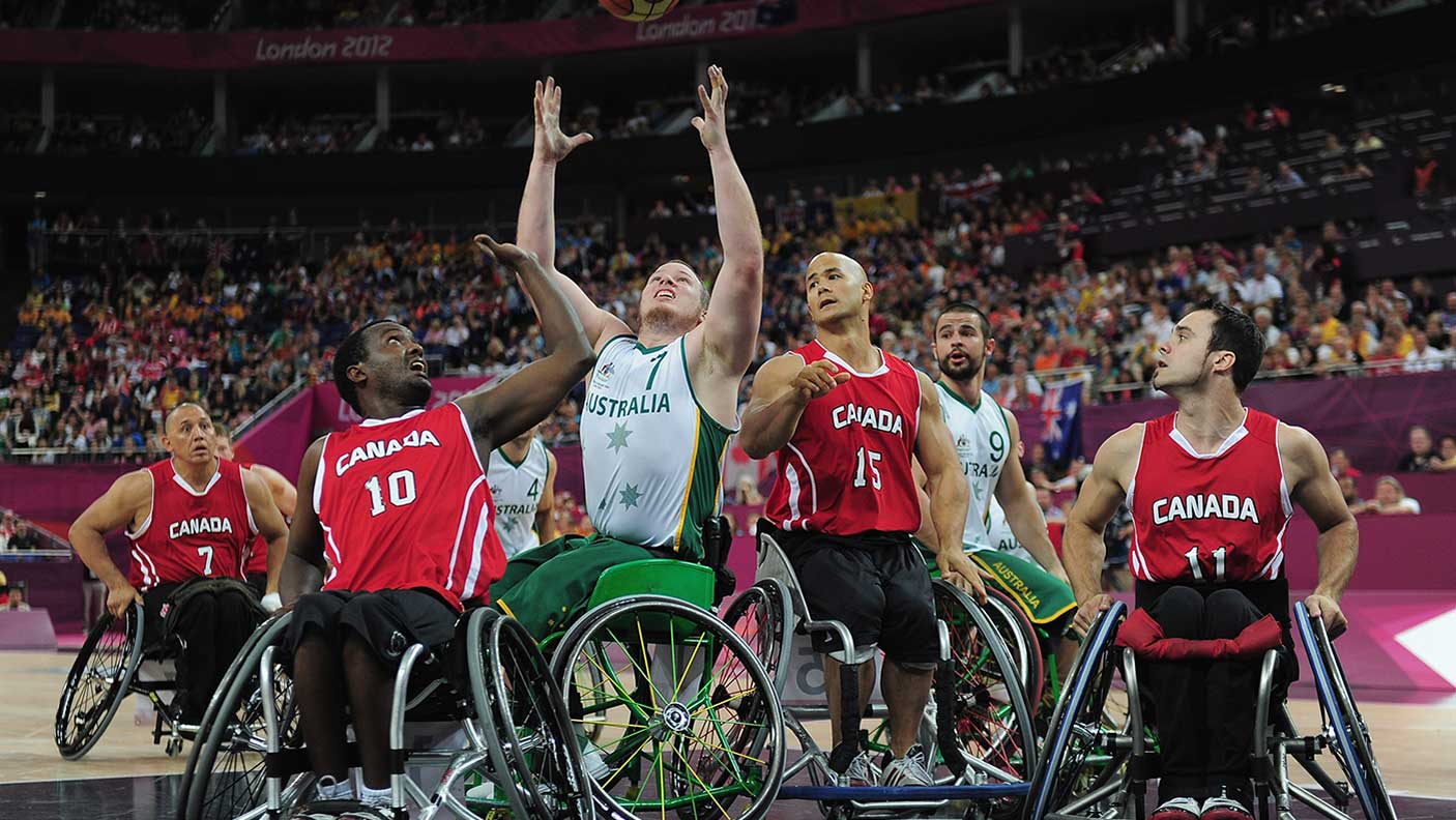 Shaun Norris of Australia is challenged by Abdi Dini and David Eng of Canada during the gold medal wheelchair basketball match between Australia and Canada