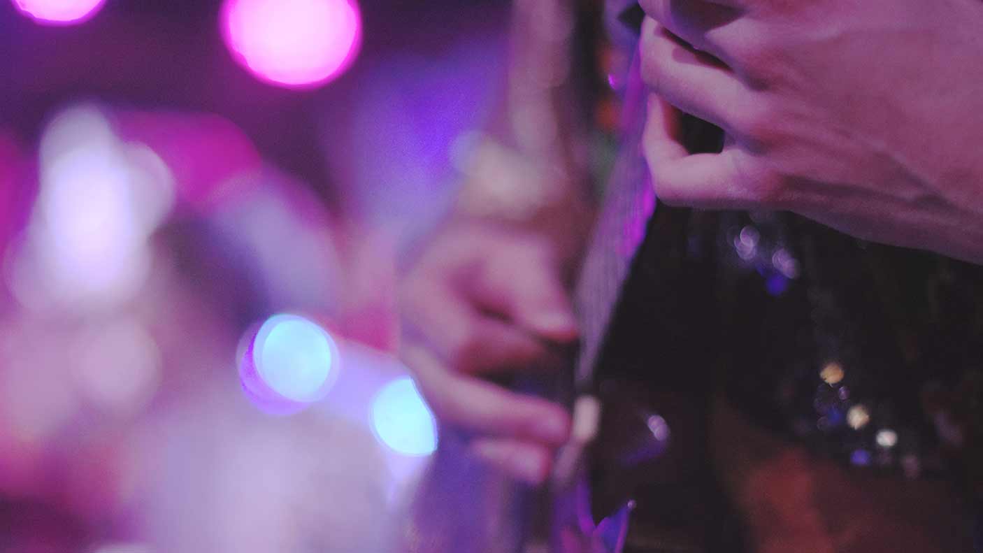 Midsection of guitarist performing at a music concert