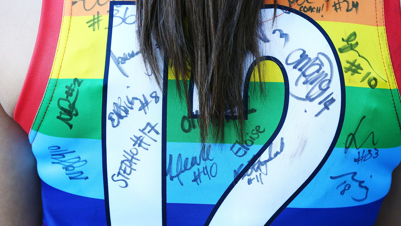 A close-up photo of a rainbow guernsey signed by people.