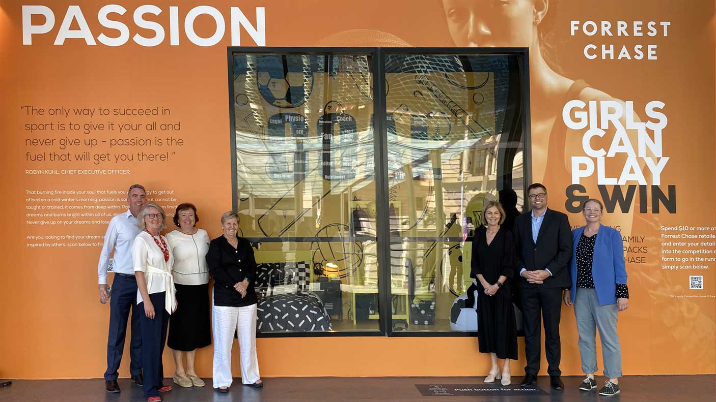 2 groups of people standing in front of a window display for Girls Can Play & Win campaign