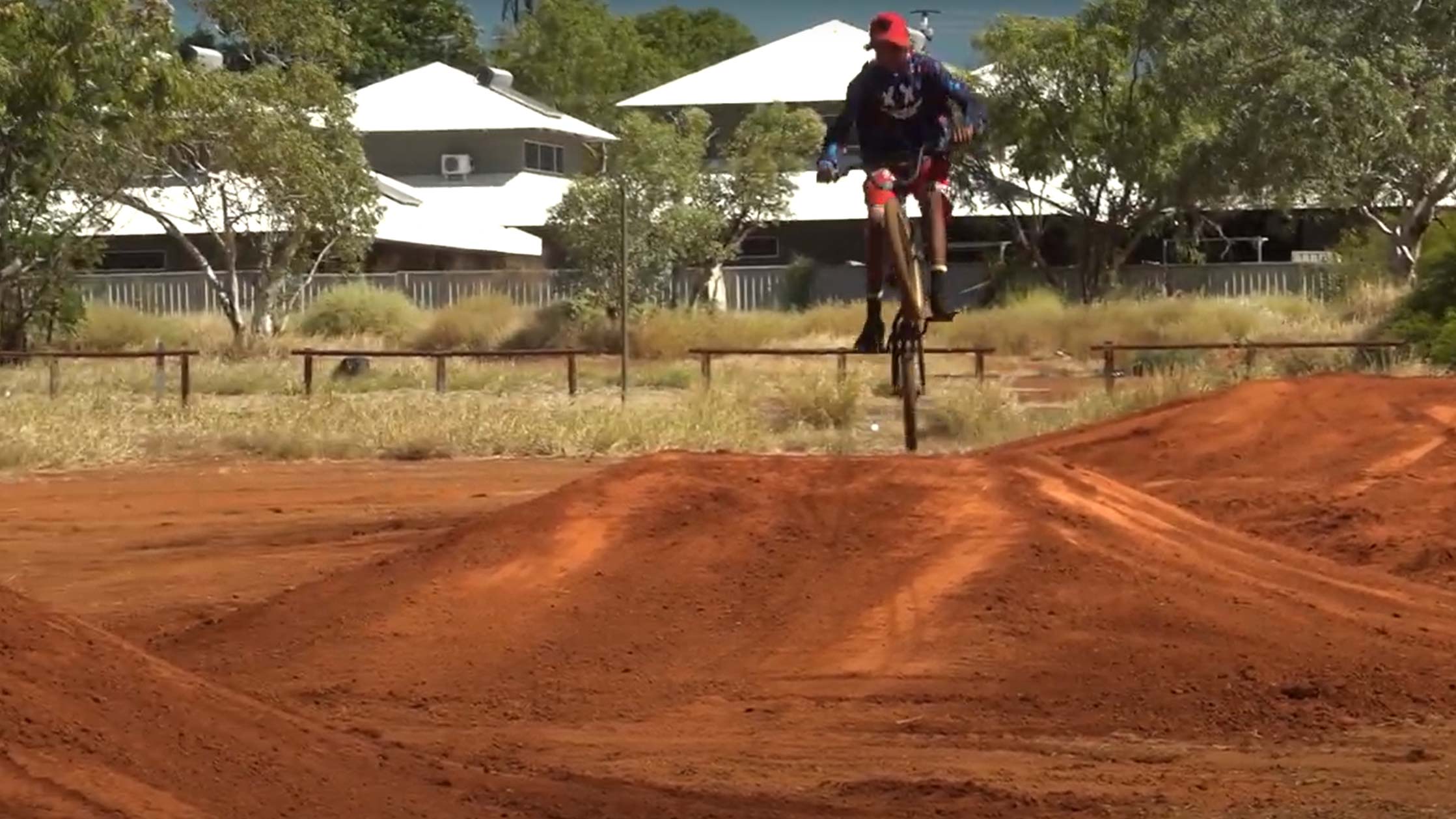 Halls Creek Bike Track Project with a boy on a bike jumping over a jump