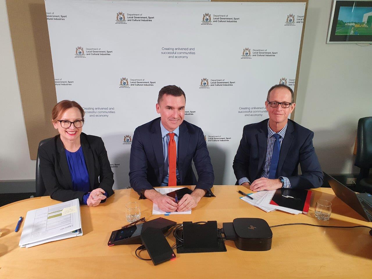 A group of 3 people sitting at a desk after presenting a webinar