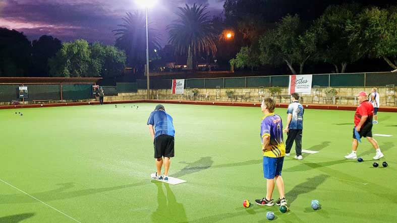 People on a bowling green lit up at night