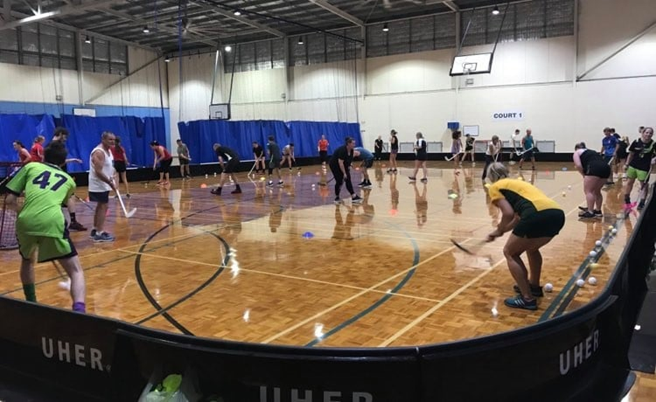 A group of people playing hockey indoors