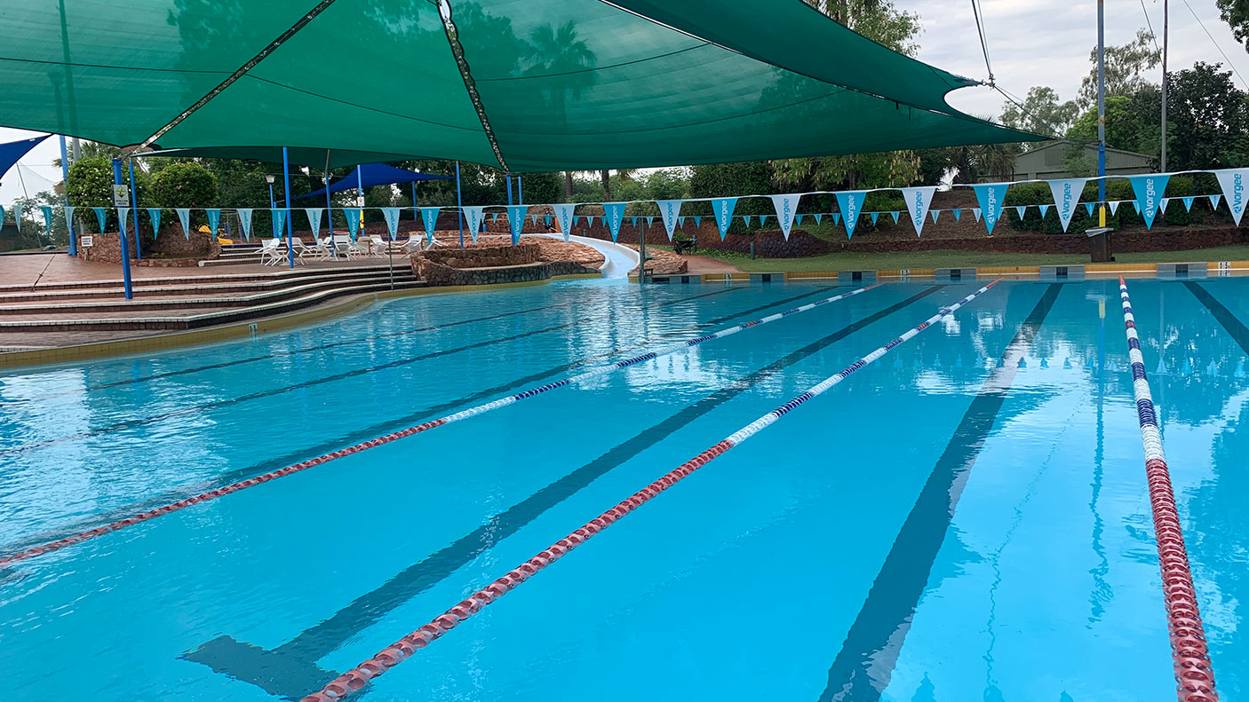 Outdoor community swimming pool lanes with a shade sail covering.