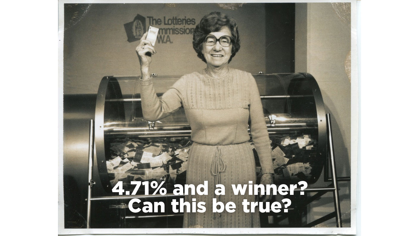 A history sepia toned image with a woman holding a lottery ticket in front of a tumbling lottery machine.