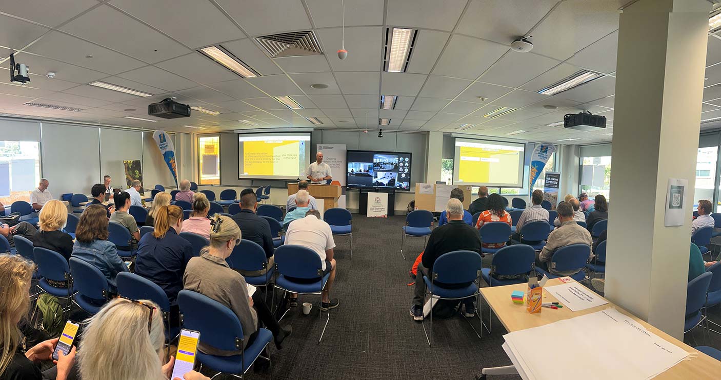 People seated in a workshop with a presenter talking at the front of the room