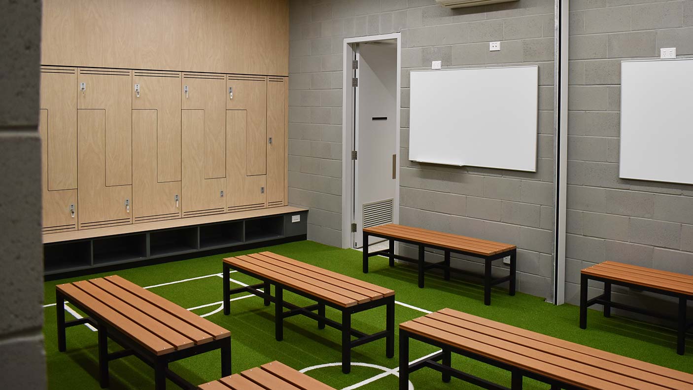 A new changroom with lockers, benches, whiteboards and a floor that looks like a football field