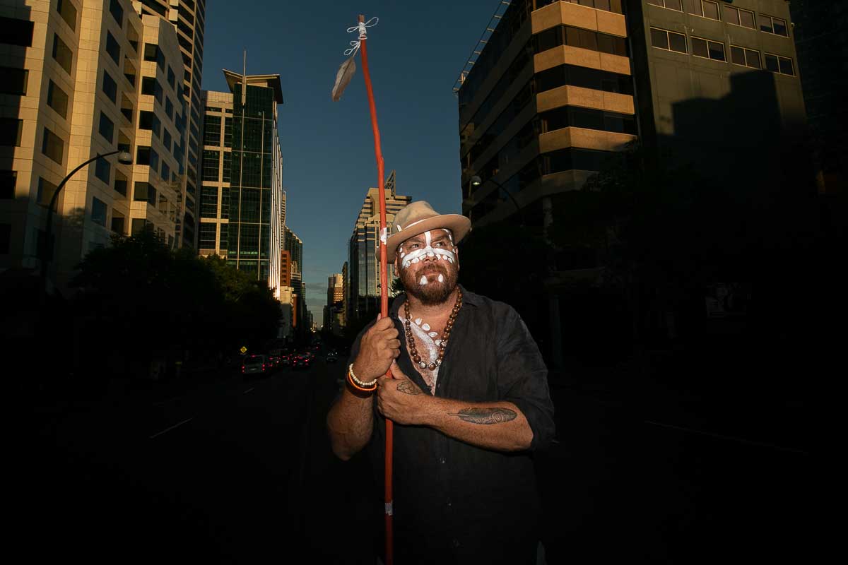 An Aboriginal man holding stick with a painted face on St Georges Terrace