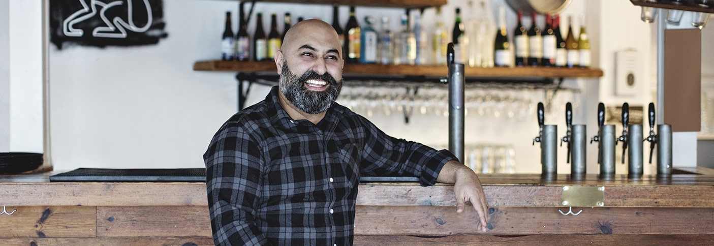 Stock image of a publican leaning on a bar