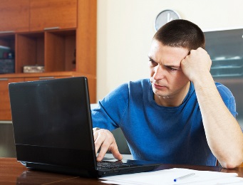 A man looking upset in front of a laptop