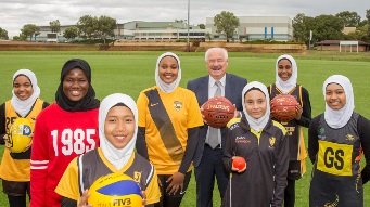 Minister Mick Murray with young women in various sporting unifroms