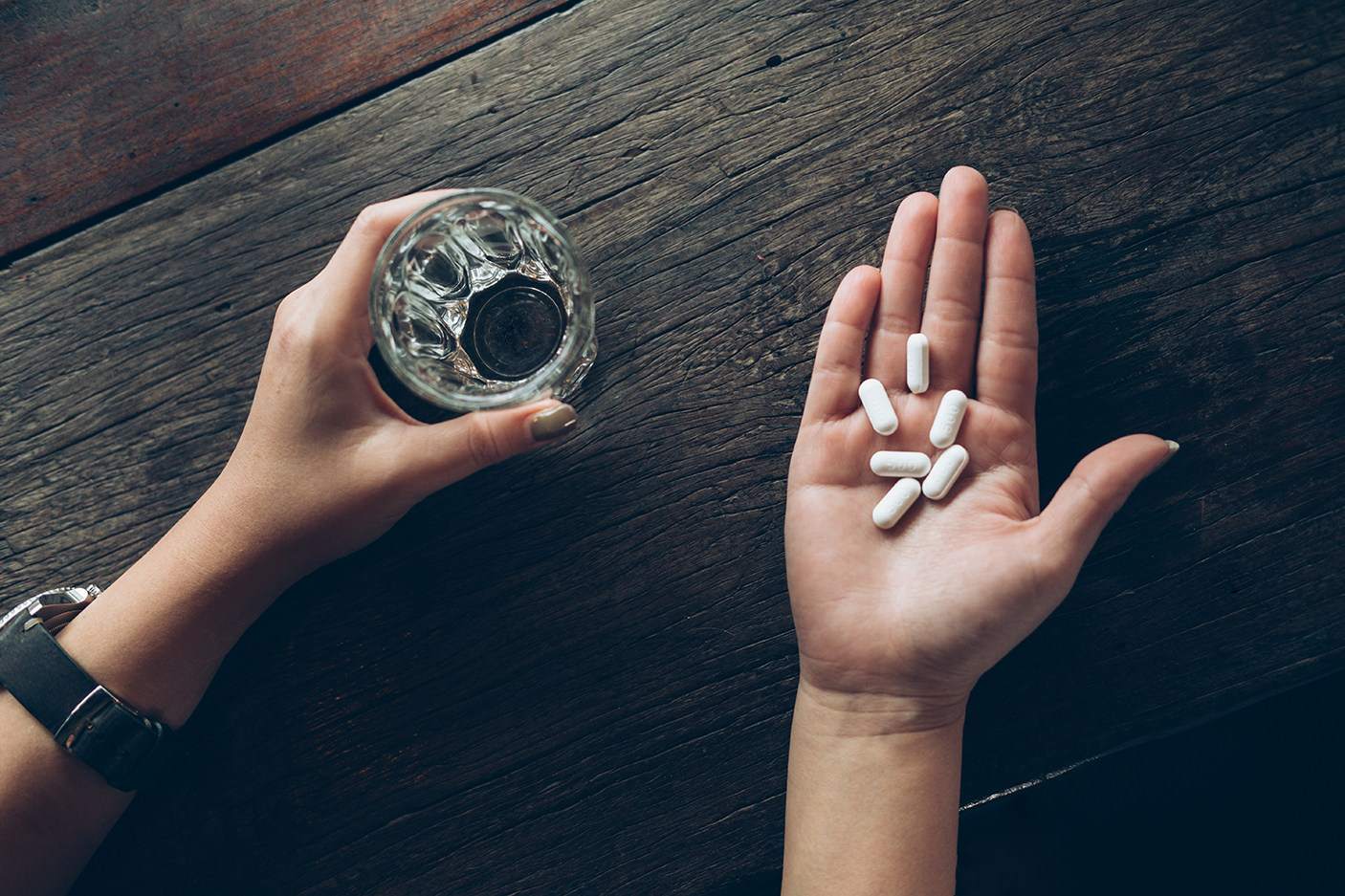 Cropped Hands Of Woman Holding Pills And Drinking Water In Glass - stock photo