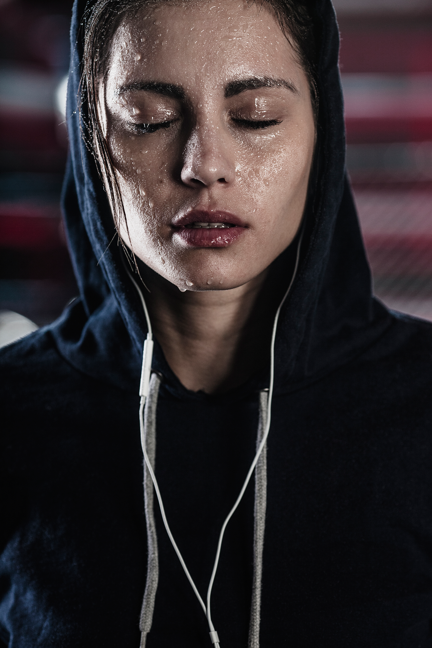 Woman in hooded shirt with sweat on face at gym - stock photo