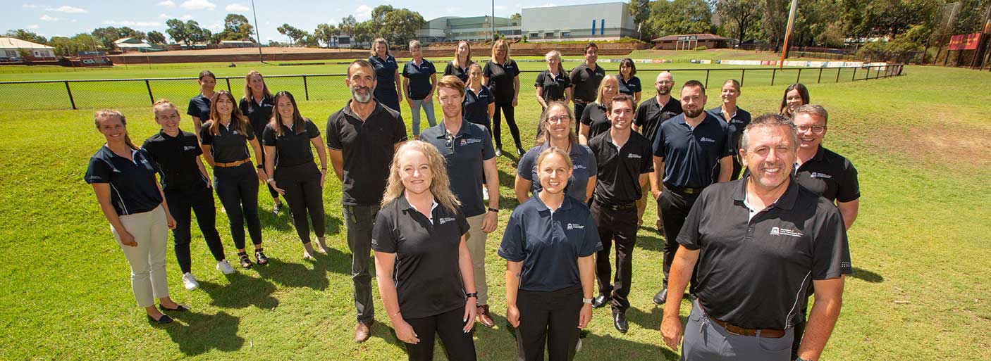 A group of staff members standing together beside a football oval