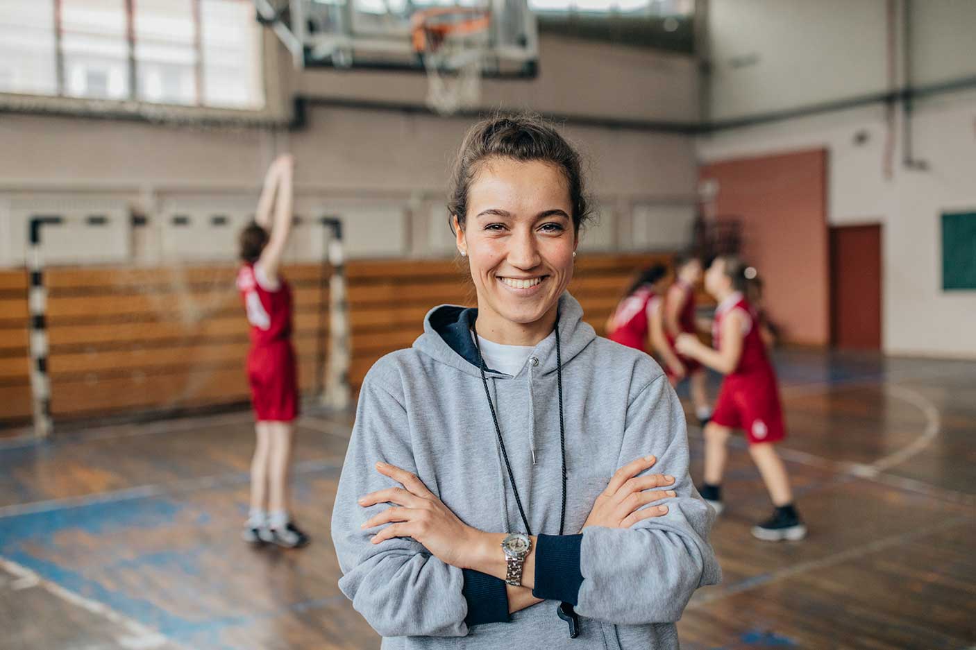Group of people, woman basketball coach and teenage girls basketball players. woman coach is standing in front of players.