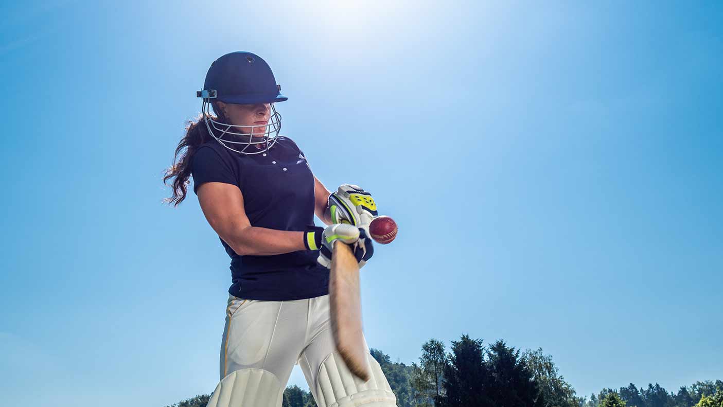 Female cricket batter hitting the ball