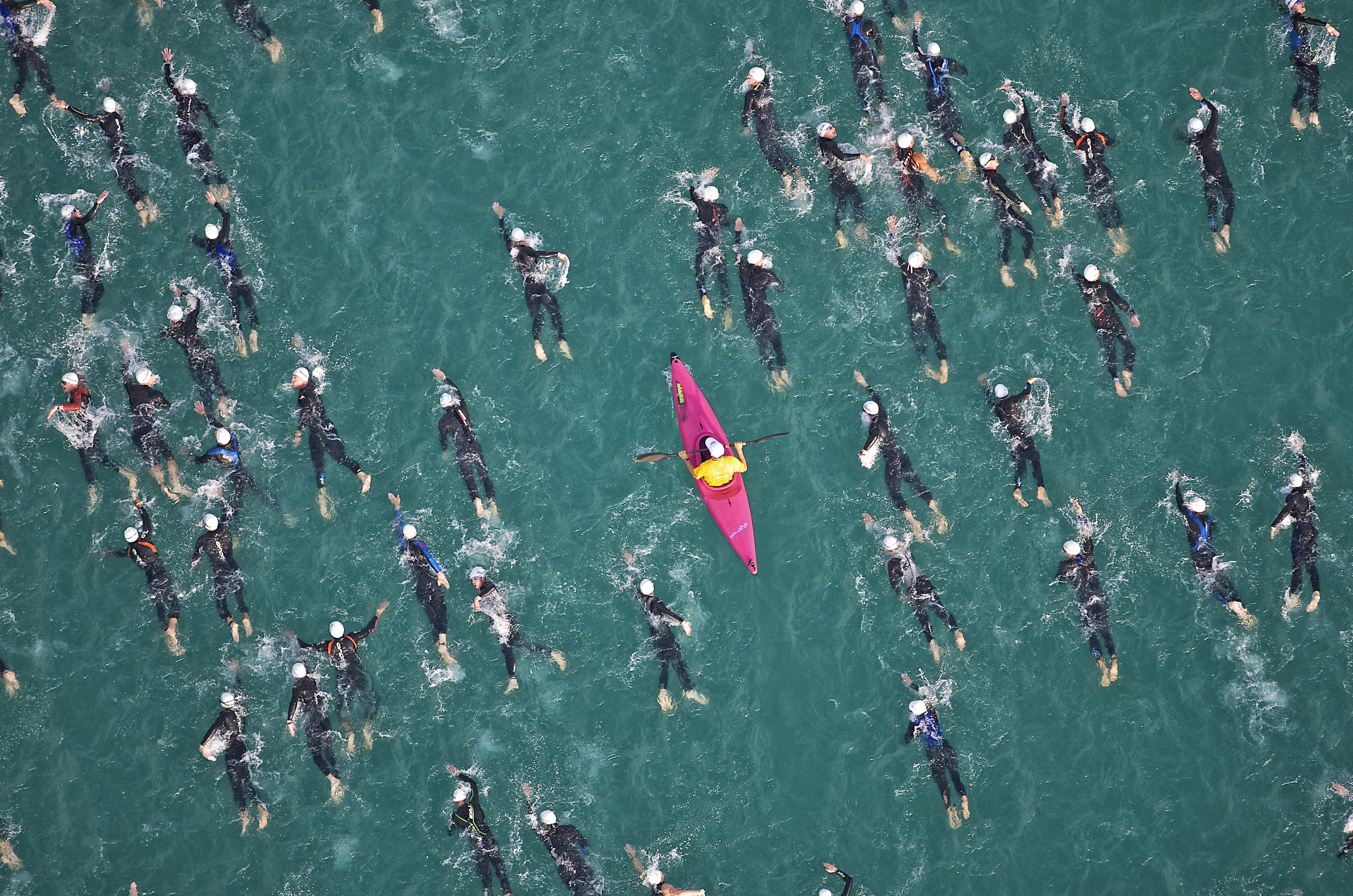 A kayaker in the ocean amongst a group of open water swimmers