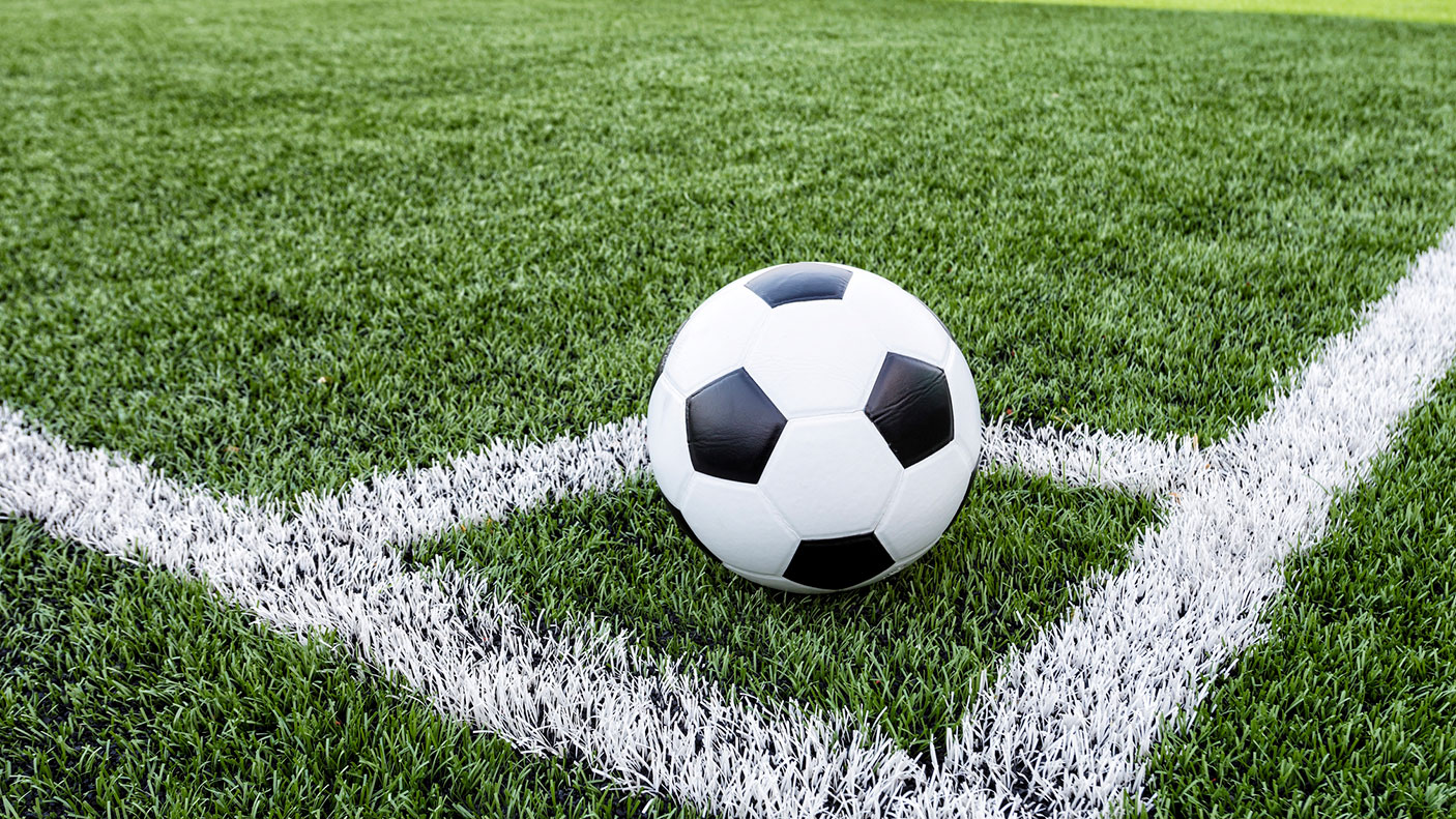 Soccer ball in the corner of a grass pitch.