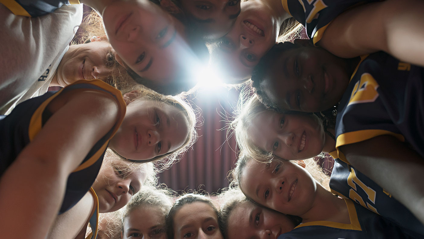 A group of players and their coach in a team huddle.