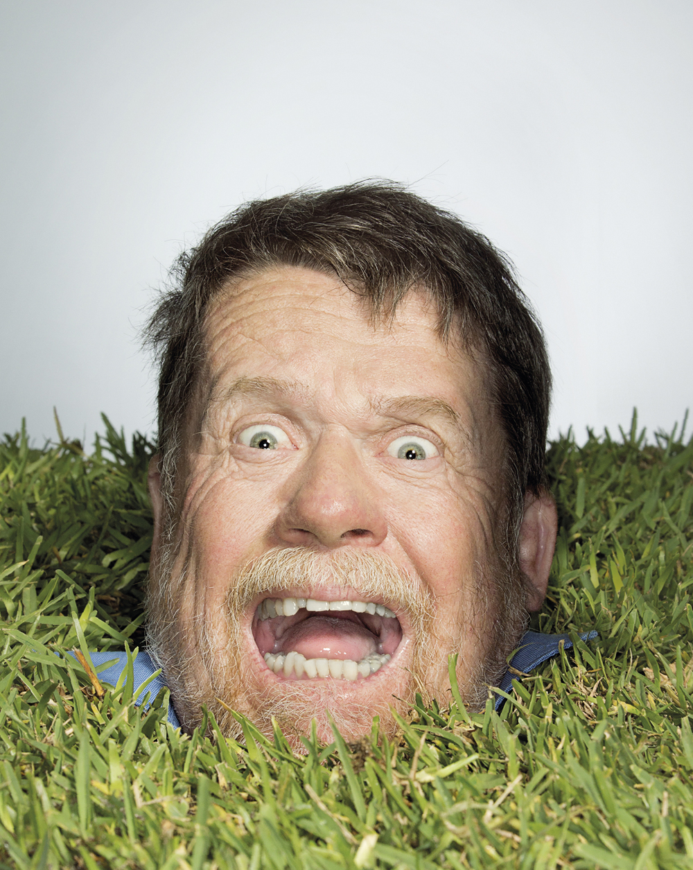 Portrait of John Forrest popping his head out of some turf